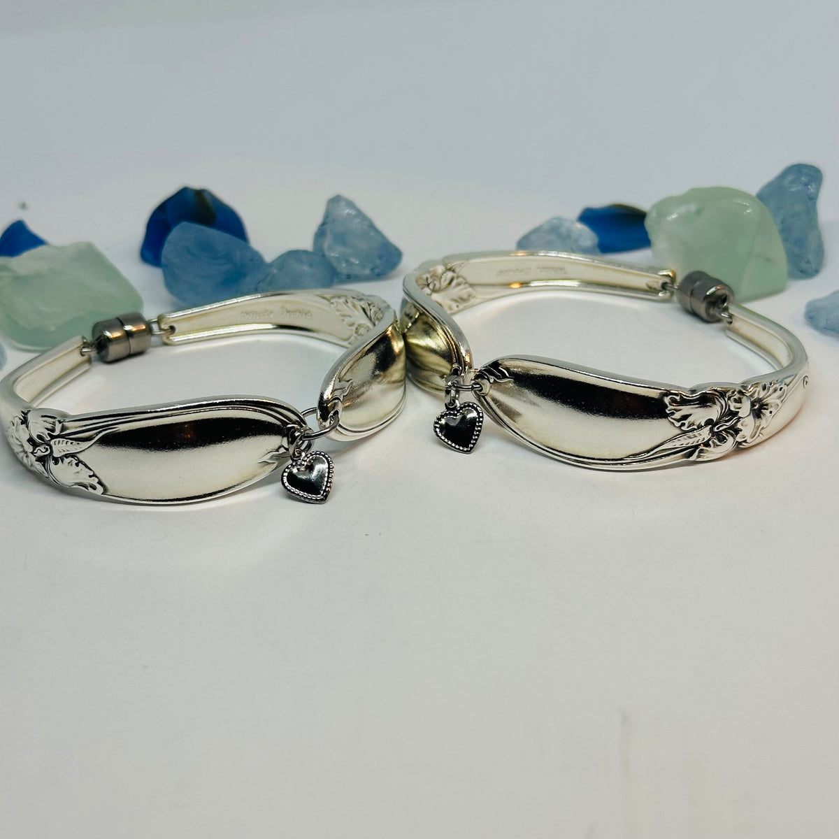 Two White Orchid 1953 silverplate spoon bracelets with heart charm and floral motif with magnetic clasp and stainless steel jump rings.