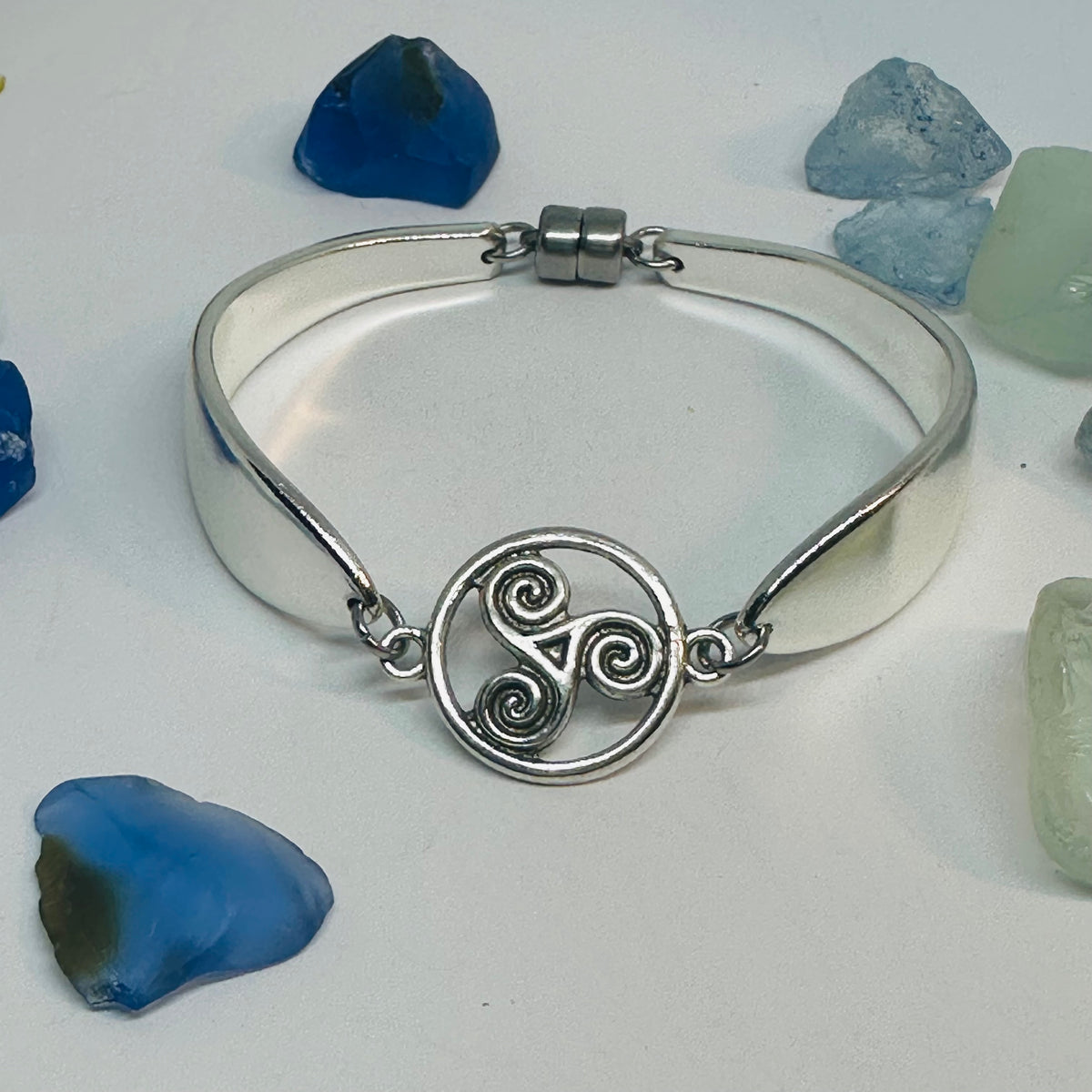 Lady Hamilton 1932 vintage spoon bracelet with a triskele Celtic connector charm, shown on sea glass.