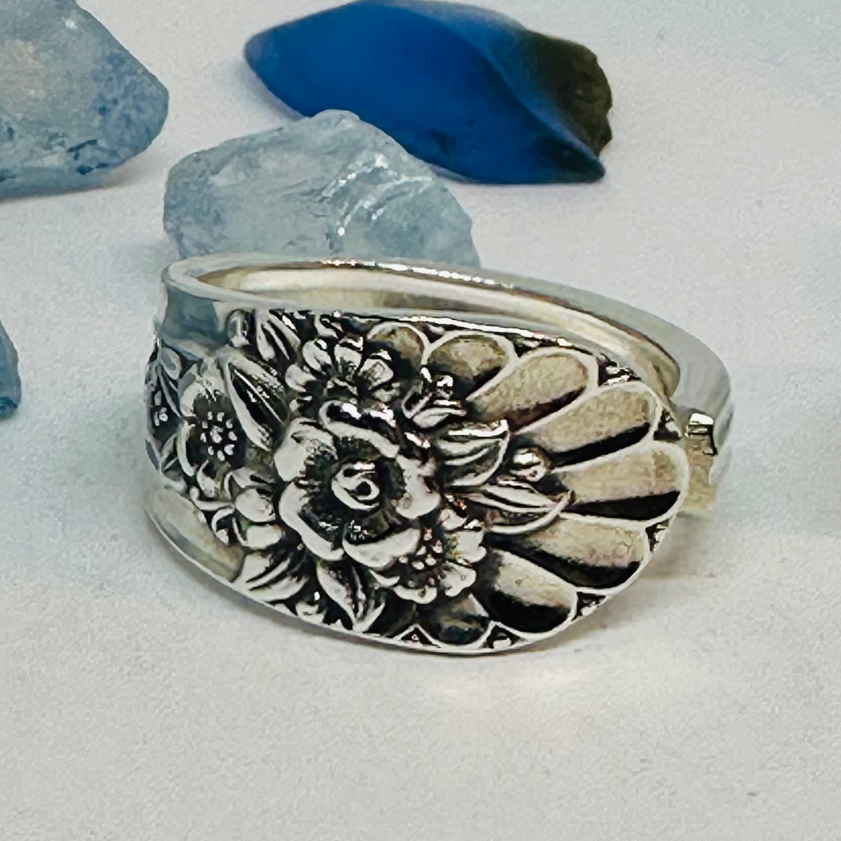 Close-up of a floral Jubilee vintage silverware ring with a wide band.