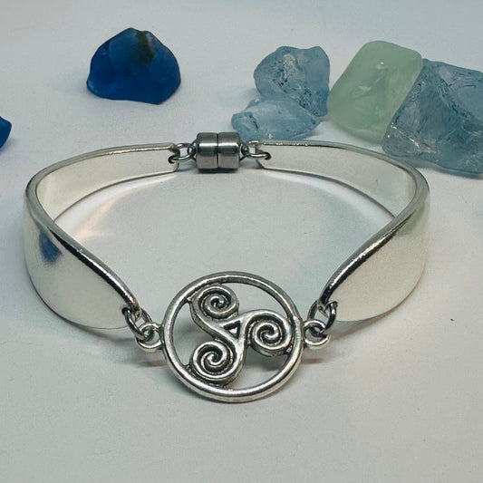 Lady Hamilton 1932 vintage spoon bracelet with a triskele Celtic connector charm and magnetic closure, shown against sea glass.