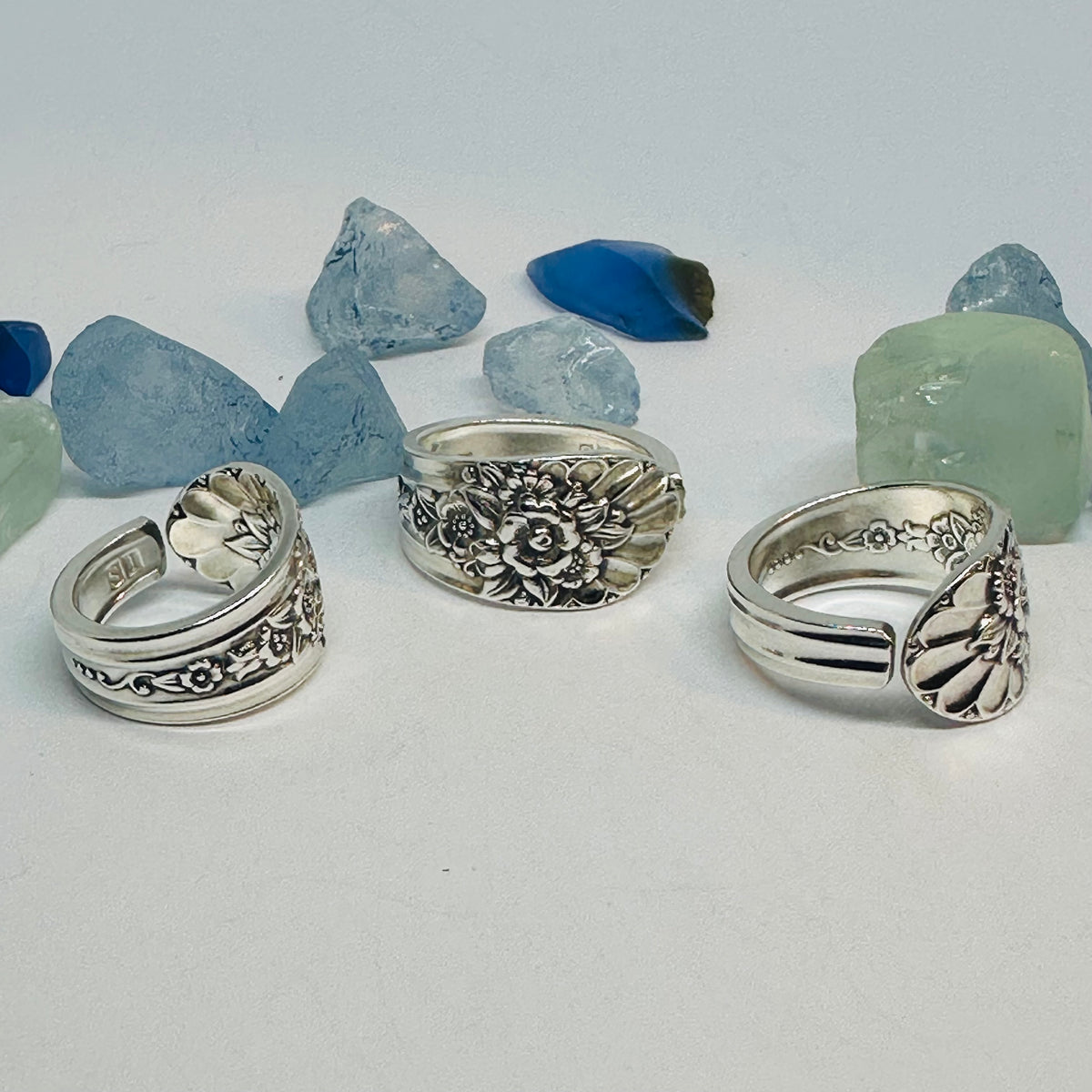 Three rings: Floral silverware rings showing their decorated fronts and band interiors.